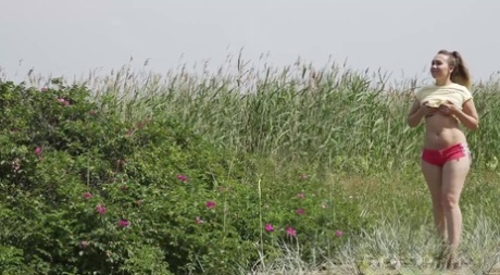 Den kaukasiske jenta Diana tisser over en tømmerstokk mens hun tar en spasertur på landsbygda.