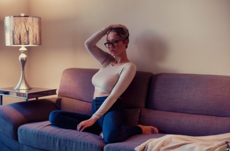 Sexet amatør Sabrina Bunny slipper sine store bryster løs på en sofa i briller