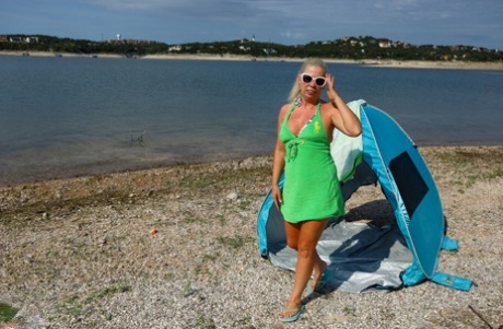 Mujer rubia mayor se desnuda dentro de una tienda de campaña en la playa