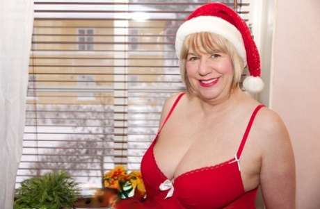 Speedy Bee, une femme britannique plus âgée, se dénude avec un bonnet de Père Noël et de longues bottes rouges.