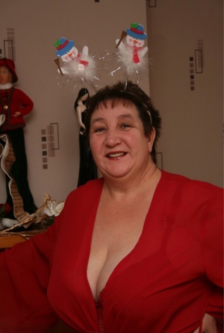 Oudere dame Kinky Carol modelleert rode lingerie en witte laarzen over de knie