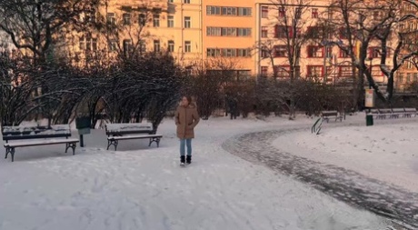 A simpática Juliia baixa as calças para fazer chichi no chão coberto de neve de um parque