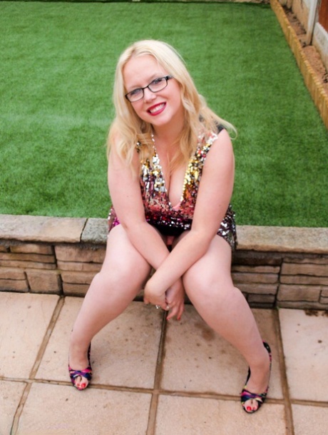 La rubia británica con sobrepeso Sindy Bust se desnuda en un muro de contención en un patio trasero