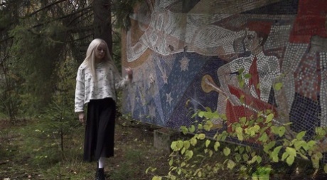 Leuk blond meisje Eva Barbie plast tegen een kunstinstallatie in de openlucht