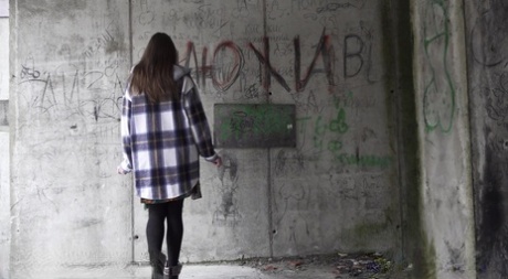 Den kaukasiska flickan Vika Lita drar ner strumpbyxorna för att kissa på en betongplatta