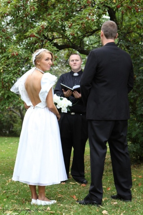 La sposa bionda Hayley Marie Coppin si spoglia su un prato mentre pronuncia i voti