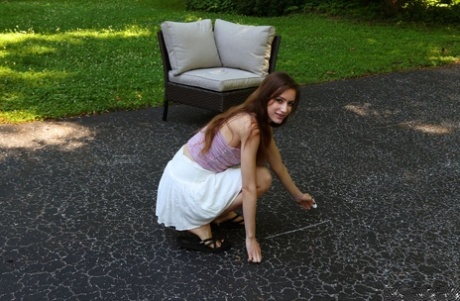 La simpatica adolescente Nadia Noja fa pipì su un vialetto mentre gioca a hopscotch