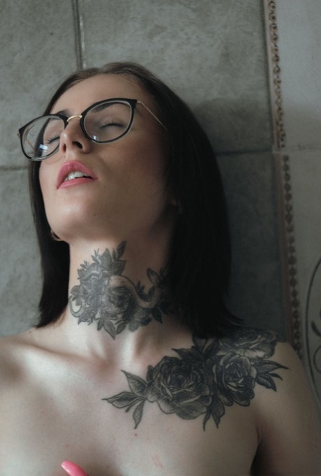 La superbe brune tatouée Pollie Star se tient nue dans sa baignoire, les lèvres en l'air.