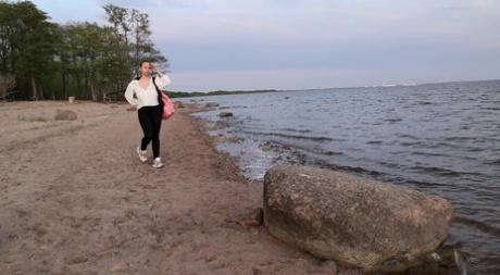 Solo girl Pinkycat pauses to piss upon a boulder while walking a beach