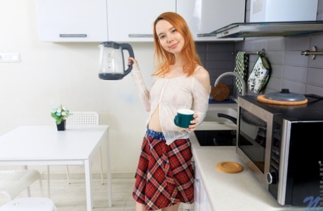 Young redhead Emily Rose gets completely naked while in a kitchen