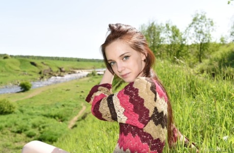 Das schlanke junge Mädchen Pala zieht ihren Pullover aus, um sich auf dem Lande zu entblößen