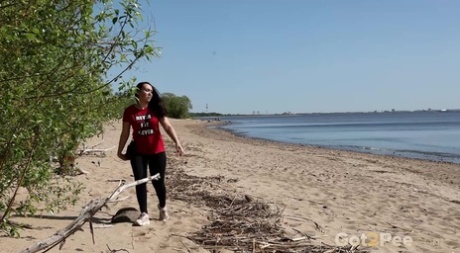 Das brünette Mädchen Anarid zieht ihre Leggings herunter, um inmitten von Büschen am Strand zu pinkeln