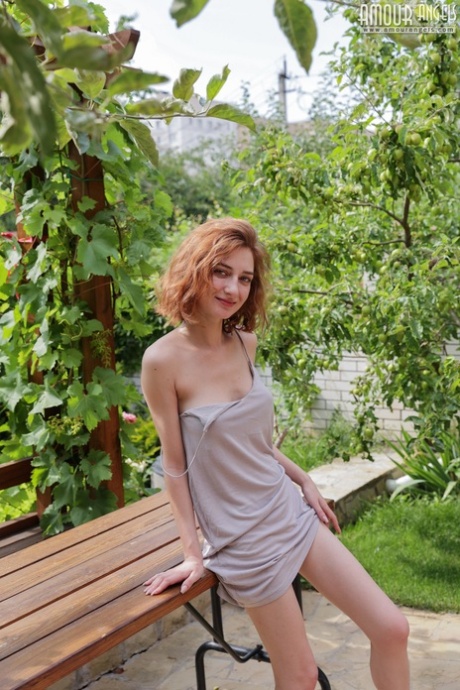 Young redhead Atika gets totally naked on a table out on a patio