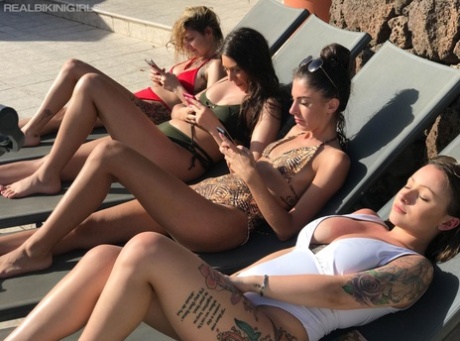 Vier meisjes trekken hun bikinitop uit terwijl ze zonnebaden op loungestoelen
