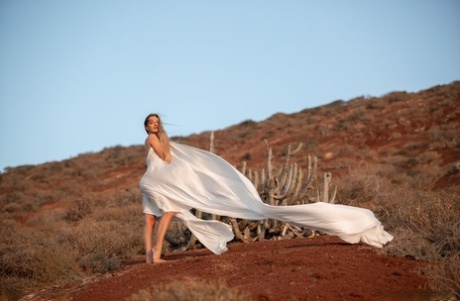 Blonde teen poses for a nude shoot at a scrubby outdoor location