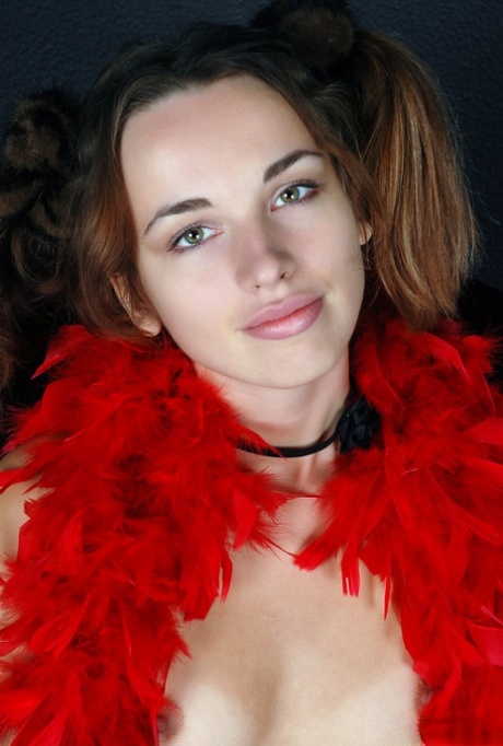 La joven Natalia B se cubre con una boa de plumas roja mientras se desnuda