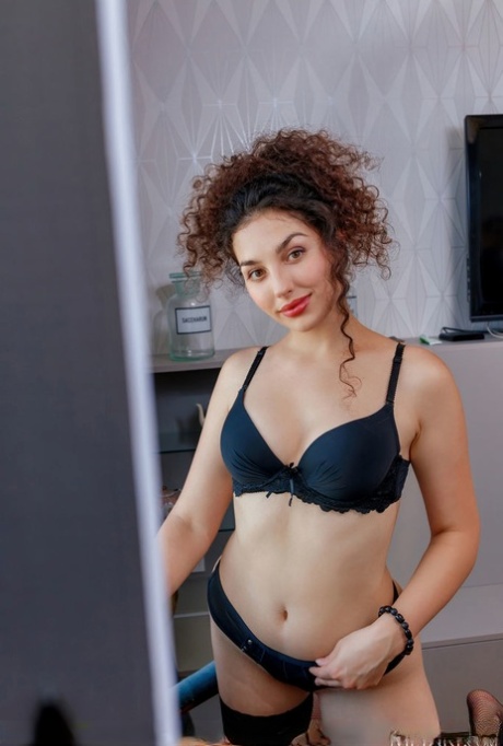 Young beauty Electra Noir lets her curly hair down while getting bare naked