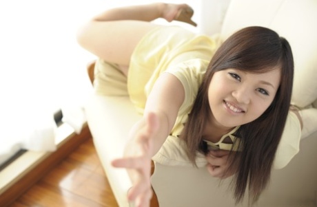 Den smukke japanske pige Erena Yamamoto ligger med mundkurv og håndjern på en seng.