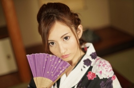 Japanese beauty Reon Otowa holds a fan before getting totally naked