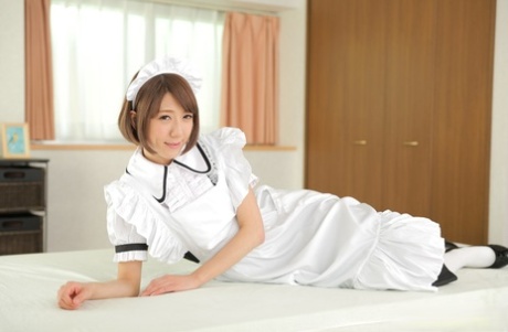 Japansk hushjelp Erina Takigawa går naken på en seng i hvite knestrømper og hæler