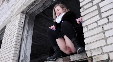 Blonde girl Alice Klay pisses in a window frame on a winter's day