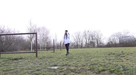 Donkerharige meisje Shalina Shine neemt een plas op een bankje in een openbaar veld