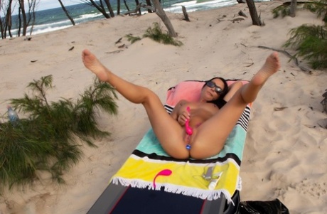 Brunette MILF Roxeanne sports a butt plug while masturbating at the beach