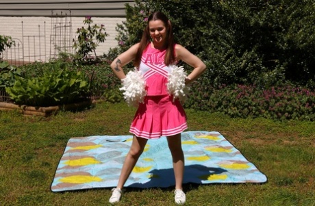 Cute cheerleader Trinity Olsen masturbates with a black dildo in a backyard