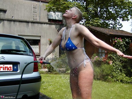 Mature woman Tiffany Pearl soaks herself with a hose while taking off a bikini