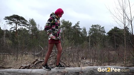 Solo girl with pink hair Vasya takes a pee over the top of some windfall