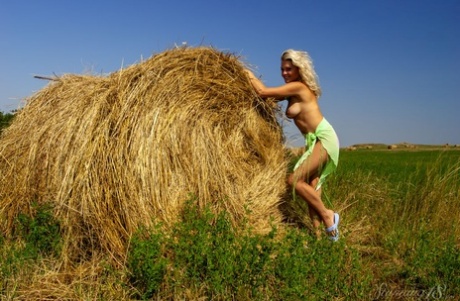 Blonde teen Elka gets naked up against a round bale in a farmer