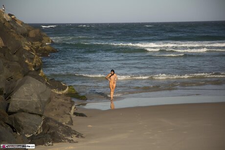 Brunette MILF Roxeanne models a yellow bikini upon a sandy beach