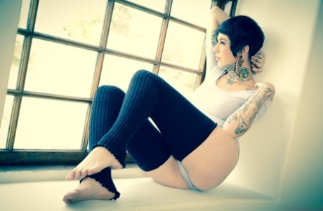 Татуированная модель Aayla Secura позирует в черных леггинсах.