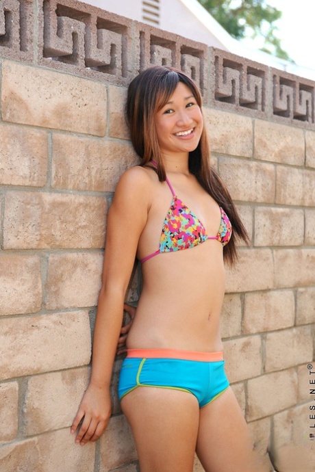 Sød asiatisk teenager tager bikinien af og afslører små bryster og spredte bryster ved poolen