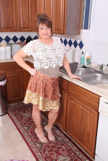 La grassa donna anziana Penney Beavers insapona le sue tette cadenti nel lavandino della cucina