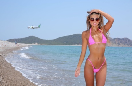 Blondinen Maria med platt bröst tar av sig bikinin för att visa sina små bröst på stranden