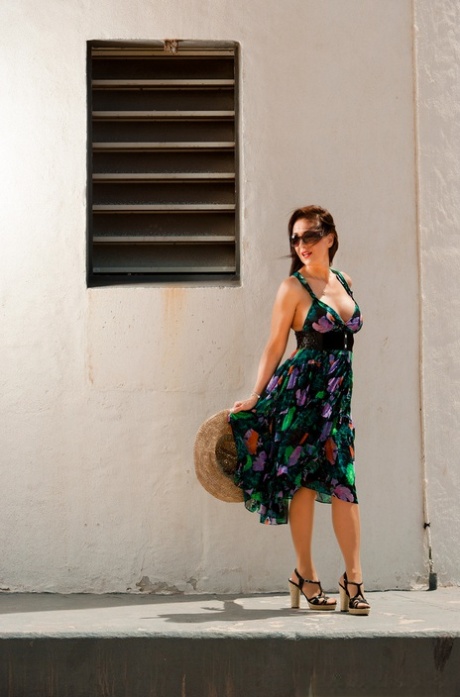 Die elegante ältere Dame Roni Ford hebt ihr Kleid am Strand mit Strumpfhose und Sonnenhut an