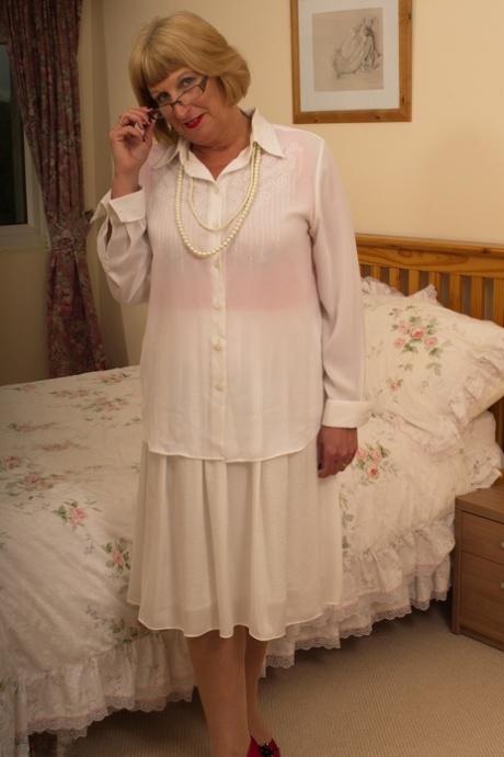 La vieja abuelita cachonda se quita tímidamente su ropa de domingo para mostrar su liguero y su culo
