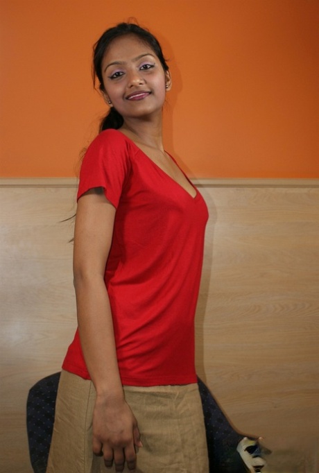 Una modelo india en solitario muestra su ropa interior con falda mientras come una naranja