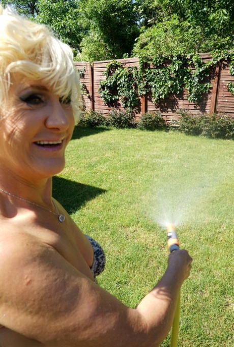 Mature blonde woman takes off her bikini while wandering around her property