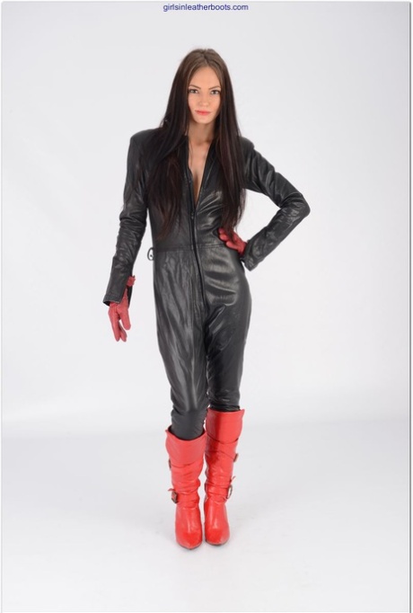 Sexy Mädchen öffnet den Reißverschluss eines schwarzen Ledercatsuits und trägt rote Handschuhe und Stiefel