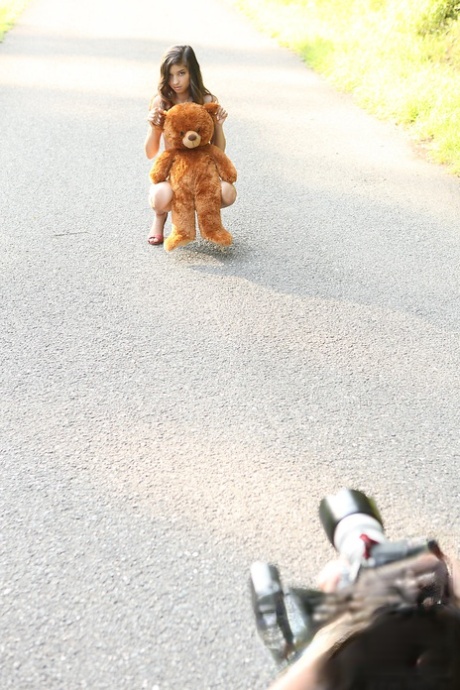 Young looking teen Nika poses naked on a road with a stuffed bear