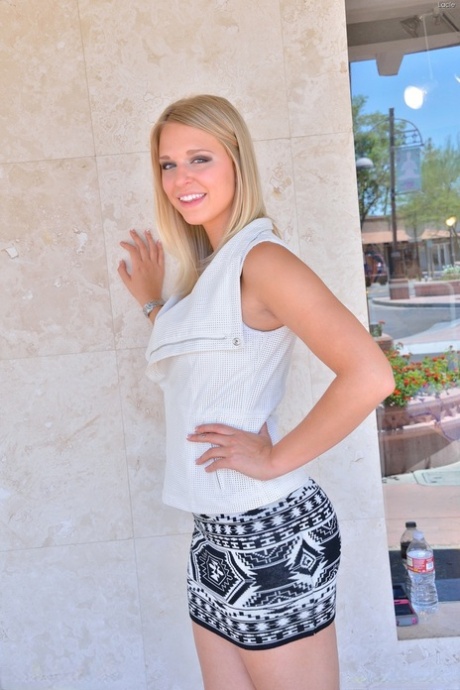 Une blonde sexy aux longues jambes, sans culotte, exhibe sa jupe haute en plein air.