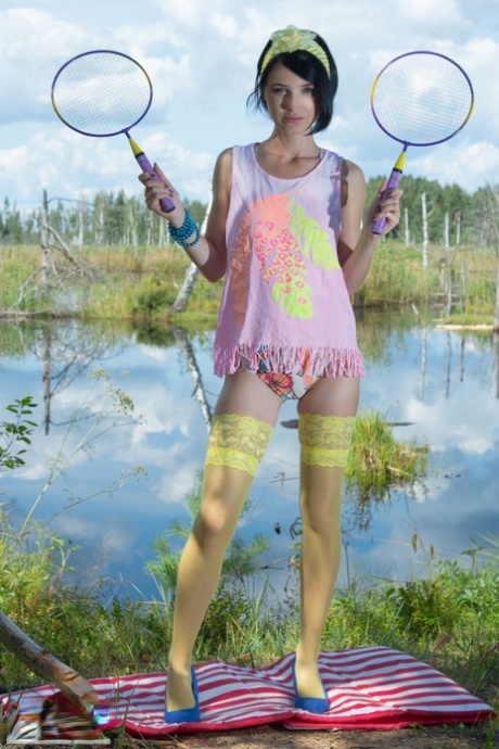 Adolescente de pelo oscuro deja sus raquetas de bádminton y se desnuda