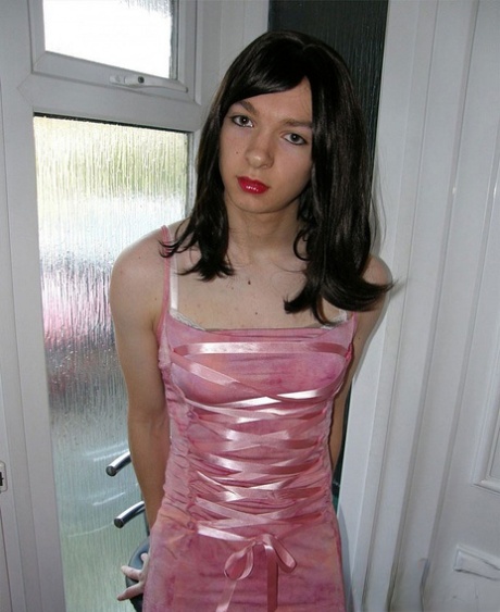 La petite TGirl montre son corps mince dans une robe rose.