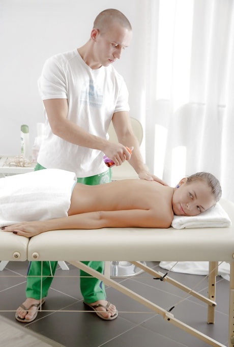 Um massagista quente está a fazer uma massagem relaxante a uma beldade oleada Carre