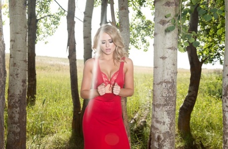 Sexy modella bionda di lingerie che si spoglia per foto di nudo nel bosco