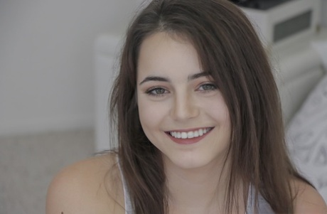 Smiley faced teen Kylie Quinn hanging out on her bed in red short shorts