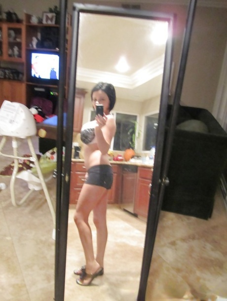 Den mørkhårede babe Loni Evans tar selfies mens hun stripper foran speilet.