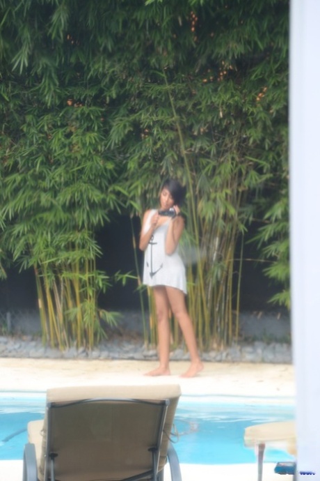 Cute ebony coed Nysha getting naked in seaside resort pool